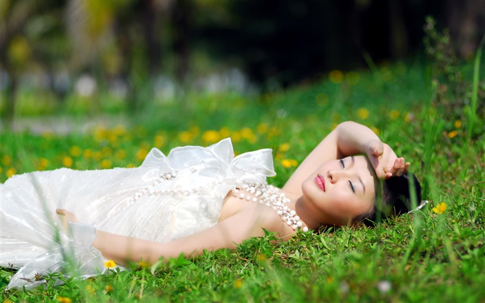 亚洲白色连衣裙的女孩躺在草地上 壁纸 图片