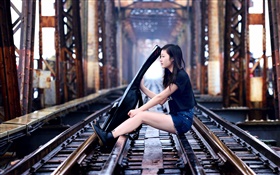 女孩坐在铁路玩吉他，桥梁
