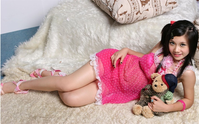 微笑粉红色连衣裙的亚洲女孩，床，玩具 壁纸 图片