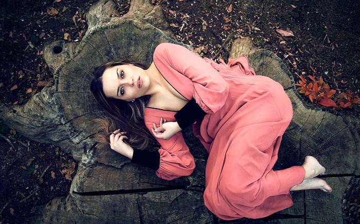 粉红色连衣裙的女孩躺在树桩上 壁纸 图片