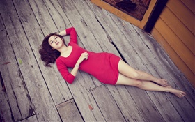 亚洲女孩躺在木地板上，红色礼服